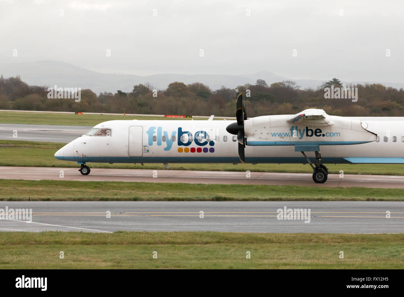 Flybe Bombardier Dash 8 Q400 medio raggio a doppio motore aereo passeggeri (G-KKEV) rullaggio sull'Aeroporto Internazionale di Manchester. Foto Stock