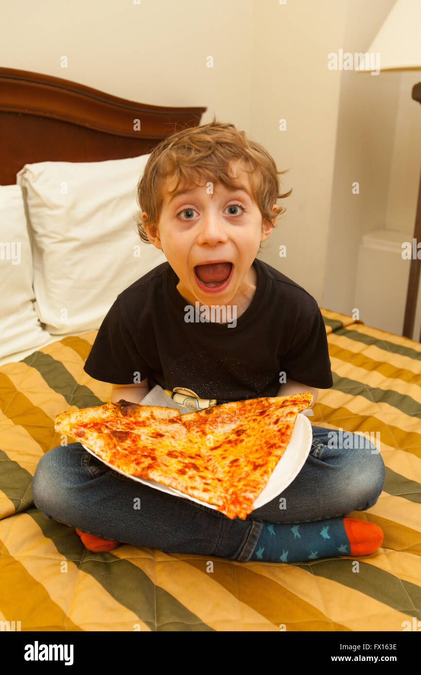 6 anno vecchio ragazzo con una grande fetta di New York Pizza, New York City, Stati Uniti d'America. Foto Stock