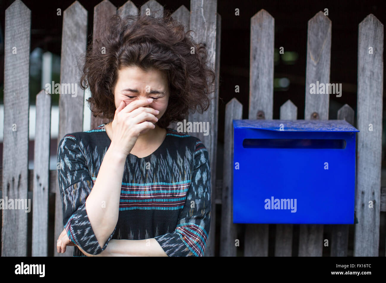 Donna asiatica sorge vicino al recinto con una casella blu. Foto Stock