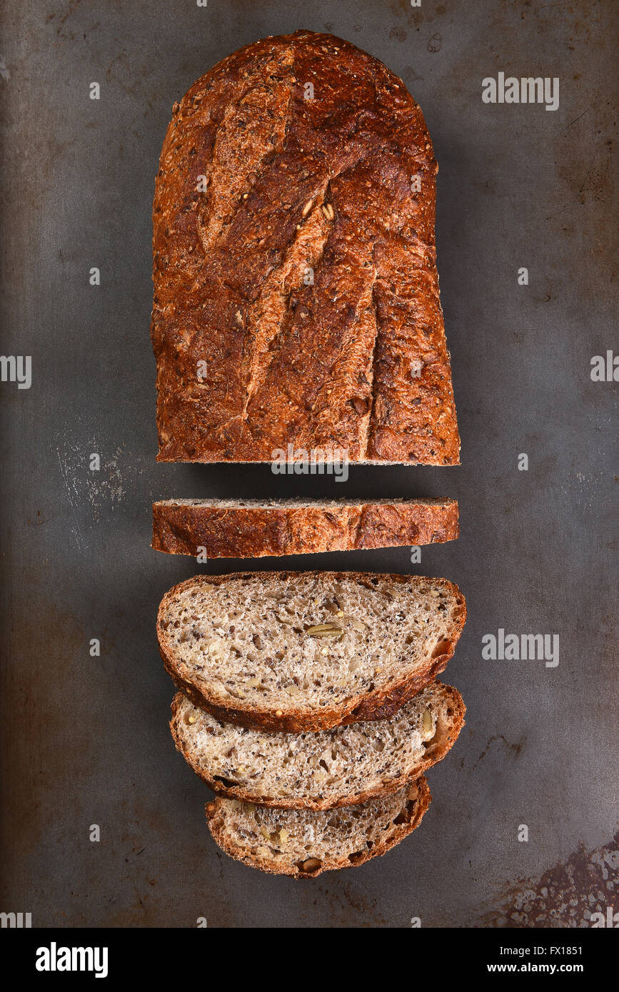 Vista dall'alto di un filone di multi-pane di grano su una placca da forno. La focaccia è parzialmente tagliata a fette, Foto Stock