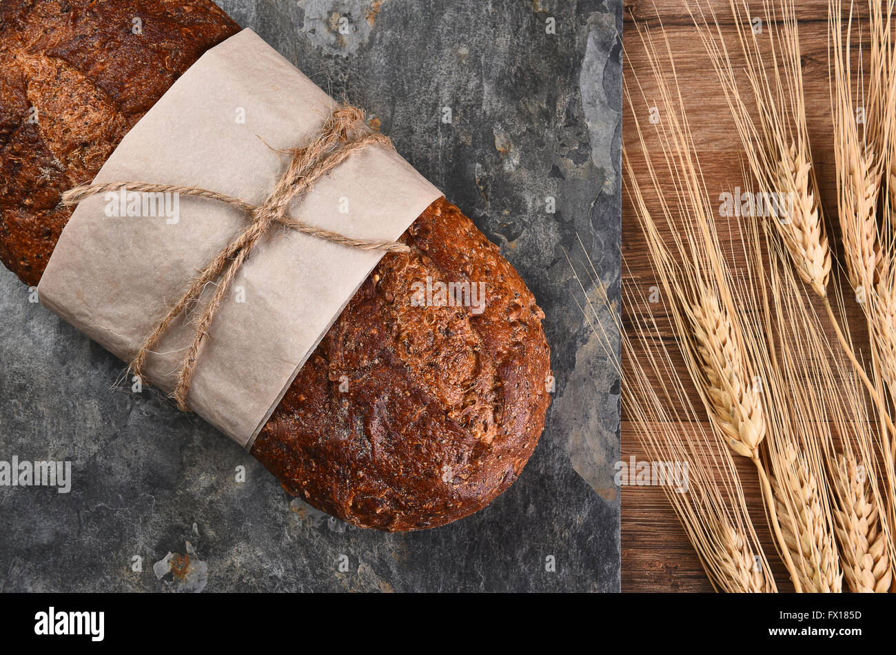 Vista dall'alto di un filone di multi-pane di grano su di una superficie di ardesia e gli steli di grano. Foto Stock