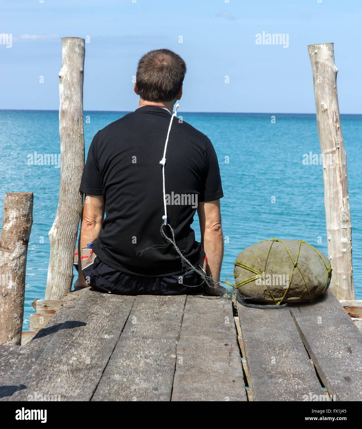 Un uomo si siede su un molo con un cappio intorno al suo collo Foto stock -  Alamy