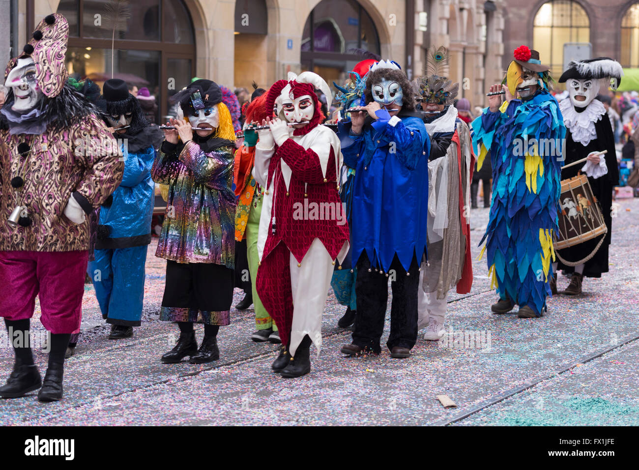 Un intero gruppo di Carnevale di Basilea i partecipanti nella loro colorati costumi marciando attraverso la parte vecchia della città Foto Stock