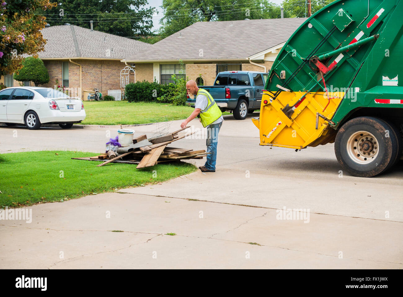 Due uomini caricare i rifiuti in un camion della spazzatura sul cestino grande giornata nella città di Oklahoma, Oklahoma, Stati Uniti d'America. Foto Stock