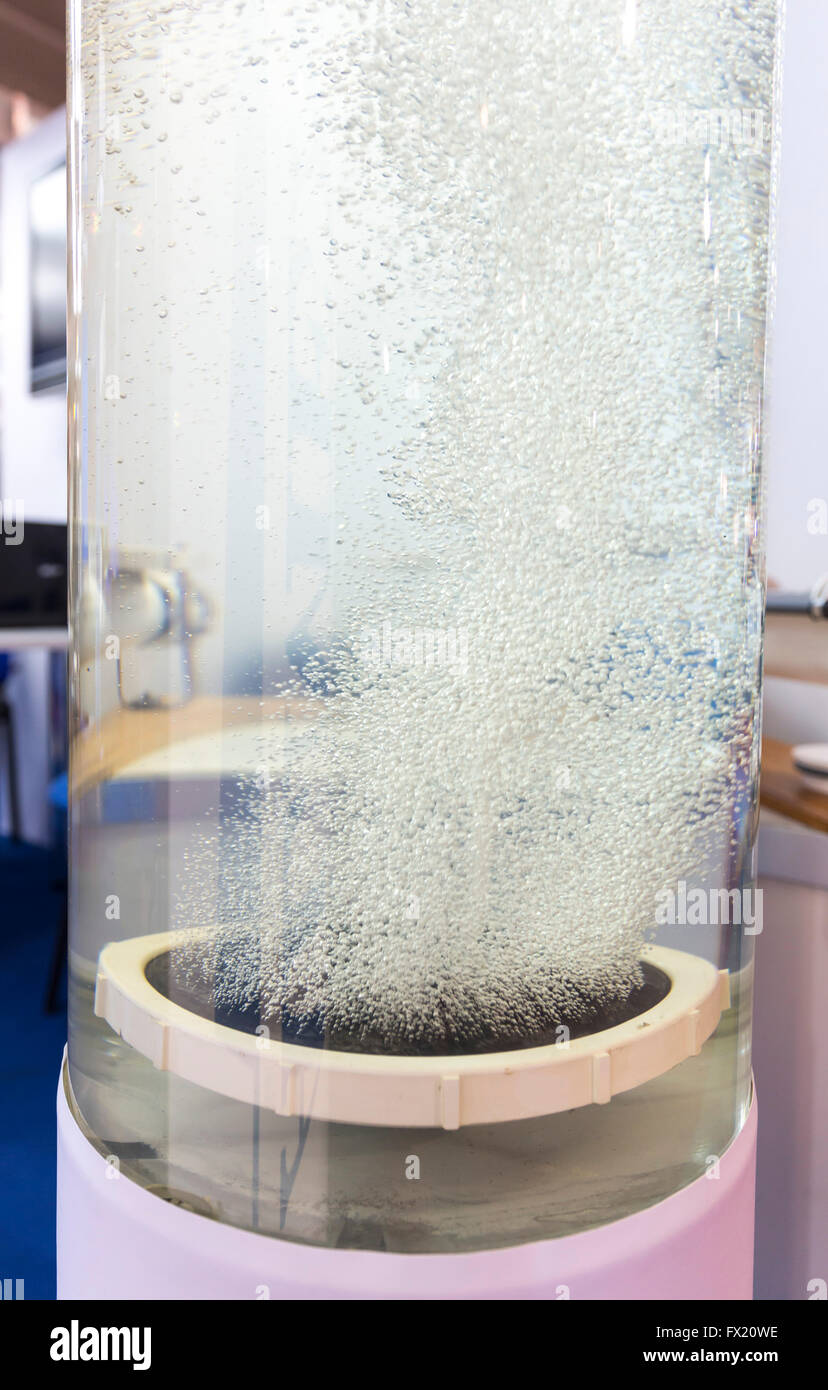 L'acqua viene filtrata in un transperant tubo di vetro. Molte piccole bolle. Acqua nuova raffinatezza sistema. Foto Stock