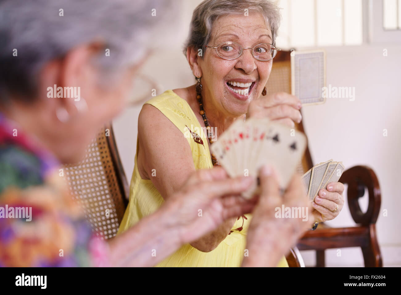 Anziani in ospizio geriatrico: gruppo di dirigenti donne giocare a carte e divertirsi insieme. Un'anziana signora vince il gioco e sho Foto Stock