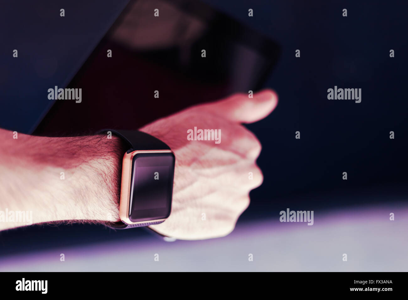 Mano maschio con due dispositivi su di esso - trandy smart watch e tablet pc. Questa persona è sempre connesso a Internet e social media con gadget moderni. Foto Stock