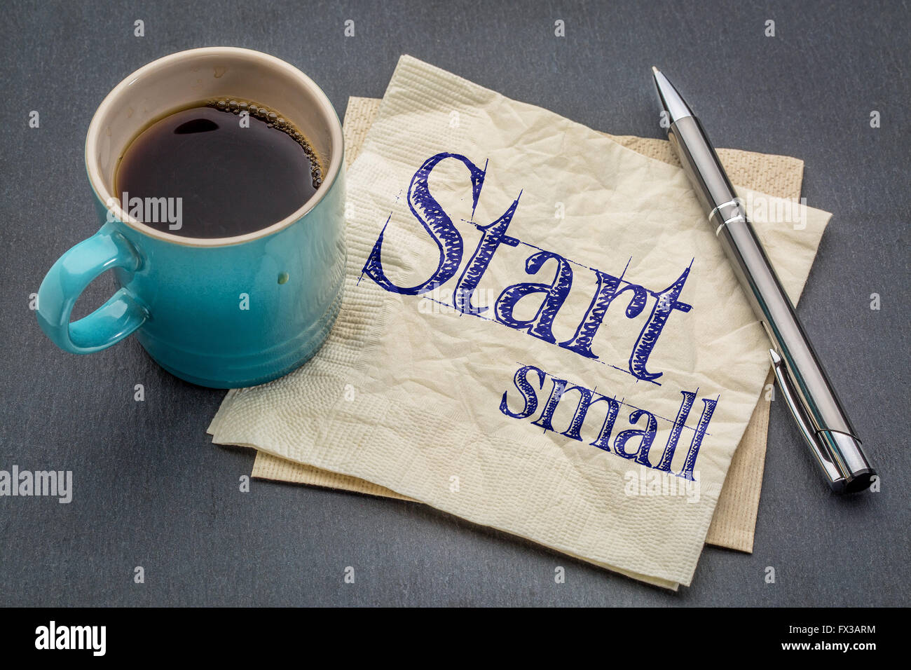 Avviare piccoli consigli - scrittura su un tovagliolo con tazza di caffè contro di ardesia grigia sullo sfondo di pietra Foto Stock