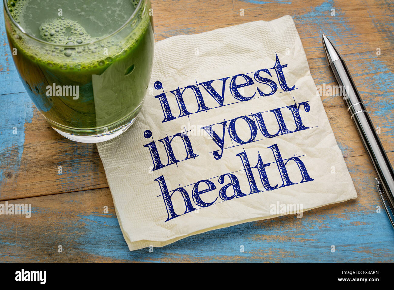 Investire nella vostra salute consigli o promemoria - scrittura su un tovagliolo con un bicchiere di fresco e verde, succo di verdura Foto Stock