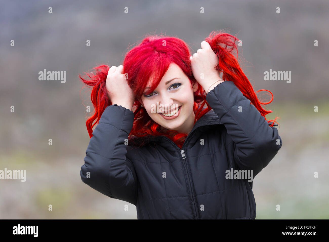Redhaired adolescente ritratto sorridente entrambe le mani tenere tenere tirare a parte capelli rossi occhi occhio contatto Foto Stock