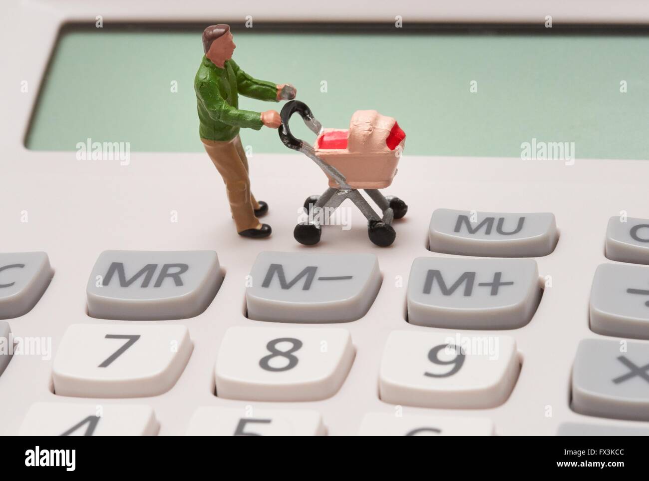 Un unico maschio statuetta in miniatura genitore spingendo una carrozzina su tasti della calcolatrice Foto Stock