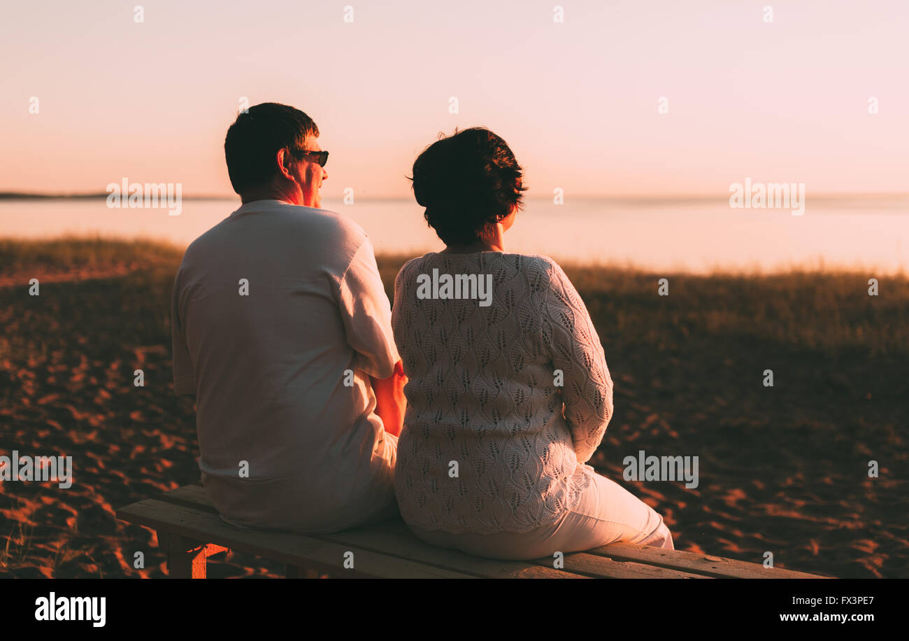 Vista posteriore di una coppia sposata una silhouette seduta su una panchina. Foto Stock