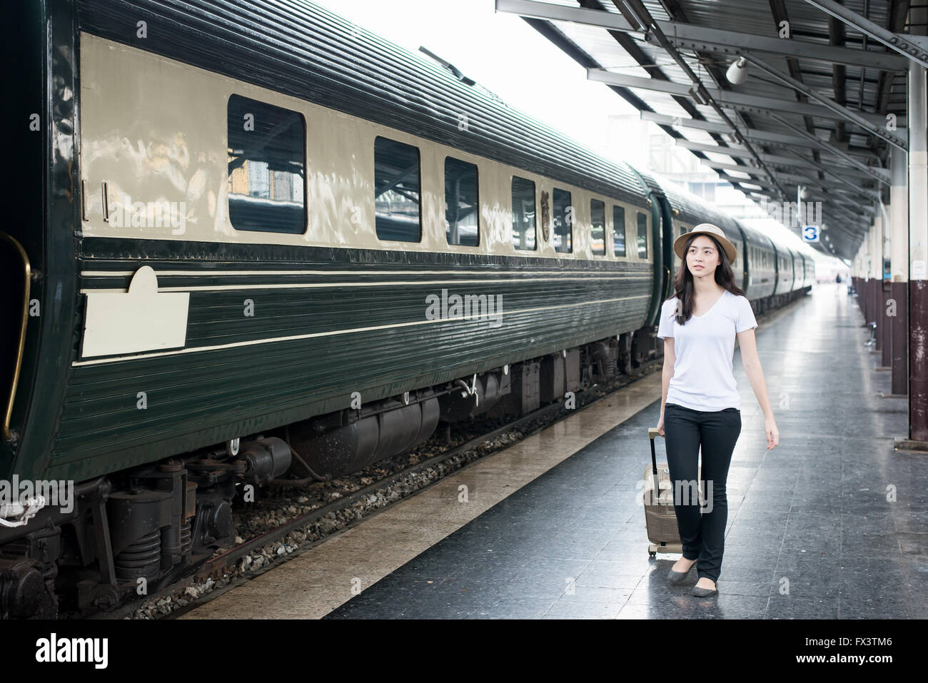 Giovani turisti asiatici con i bagagli in attesa in treno in stazione. Foto Stock