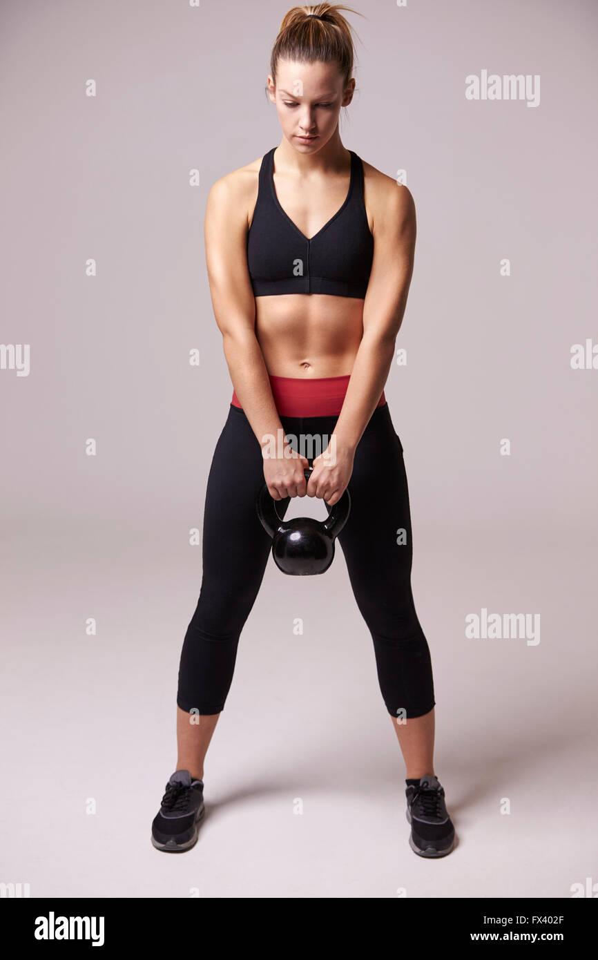 Giovane donna che lavora fuori con peso kettlebell a piena lunghezza Foto Stock