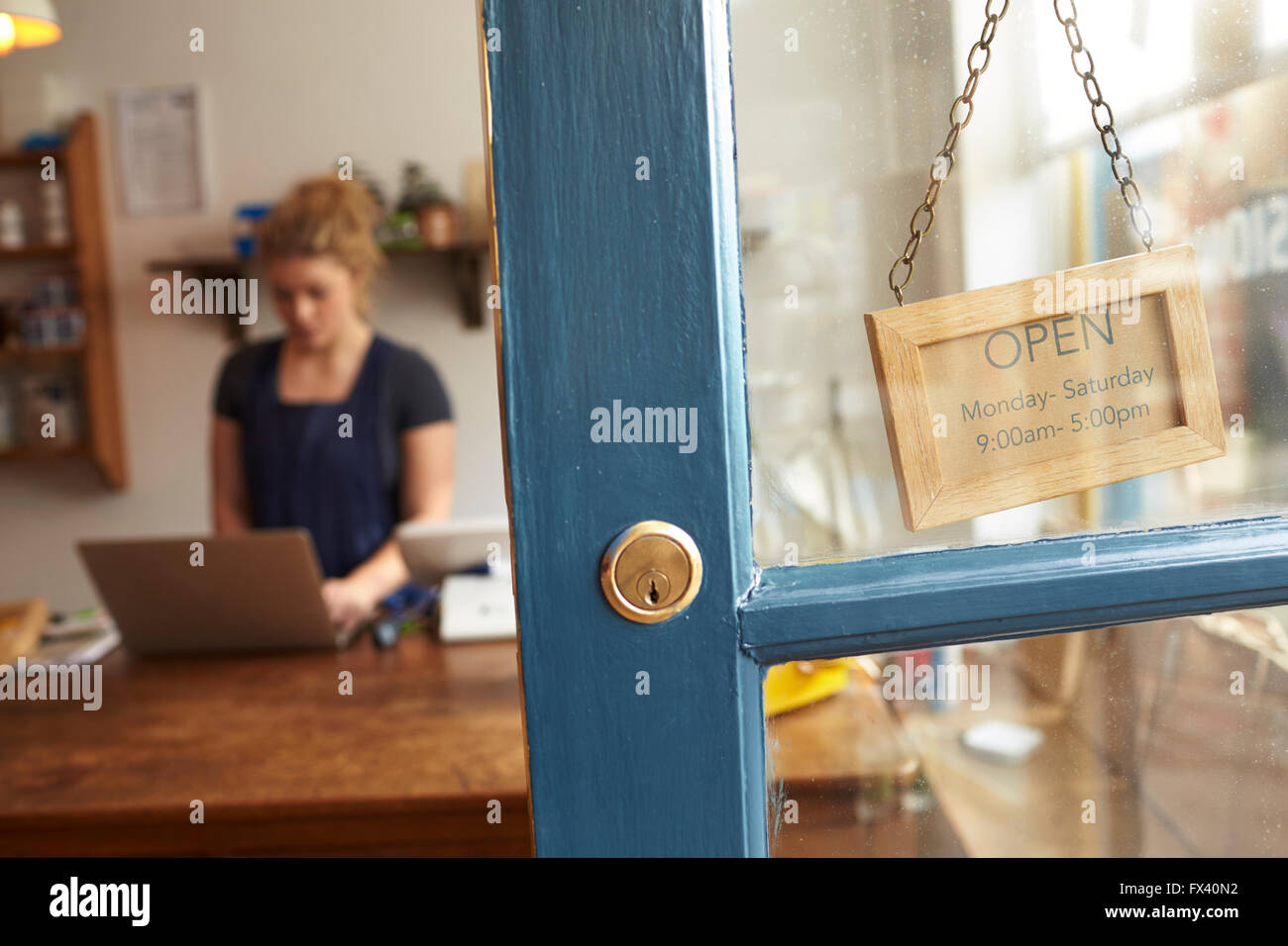 Delicatessen femmina proprietario al momento del checkout visto attraverso la porta di negozio Foto Stock