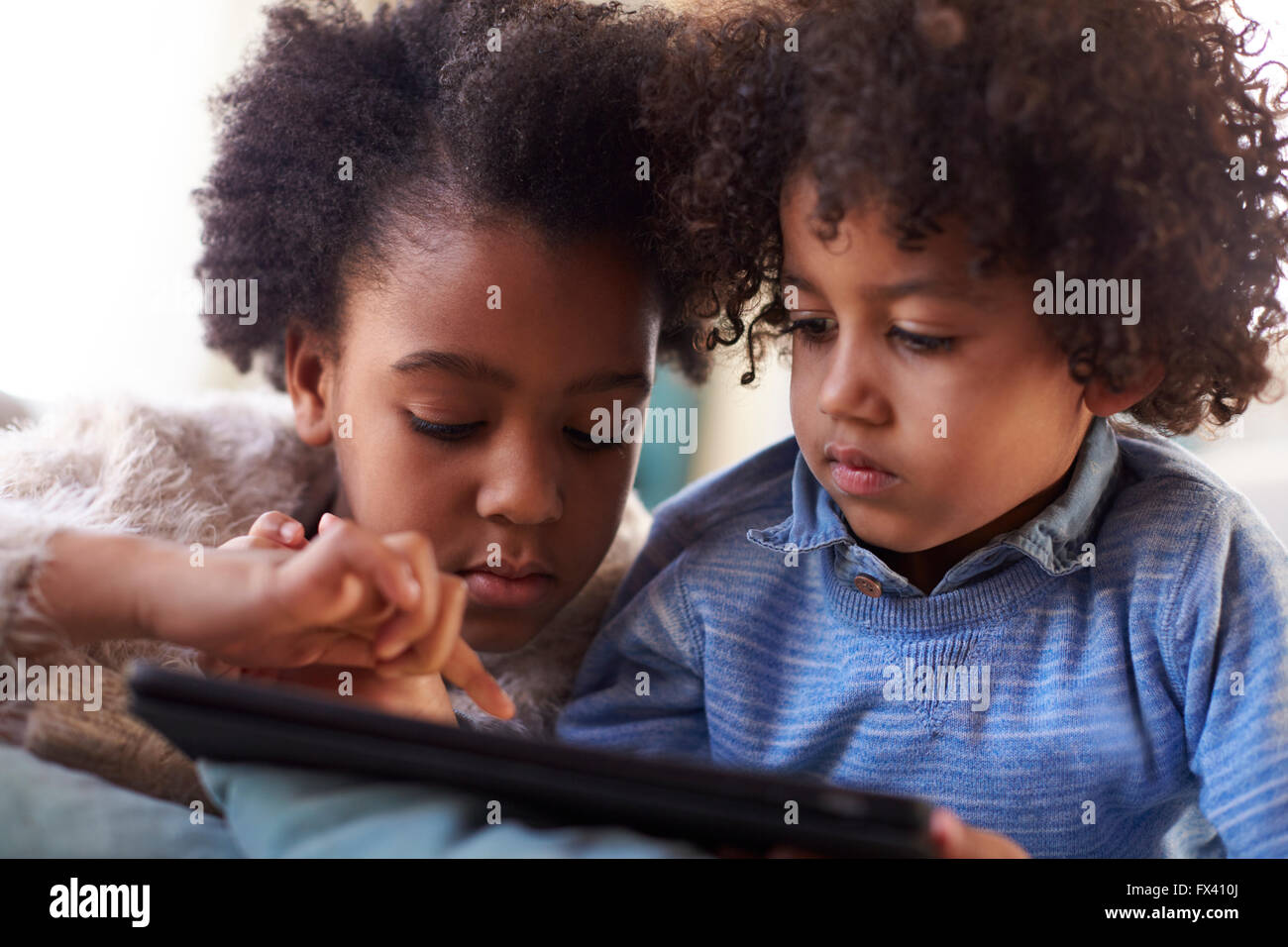 Fratello e Sorella con tavoletta digitale a casa insieme Foto Stock