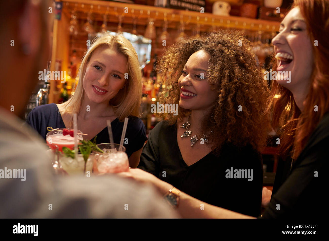 Gruppo di amici riuniti per un drink serale nel Cocktail Bar Foto Stock