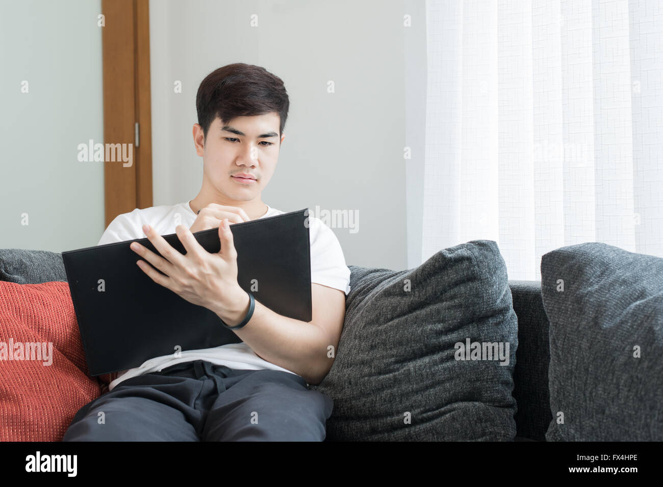 Asian Giovane Uomo di pensiero e chiedendo durante la scrittura di una carta a casa Foto Stock