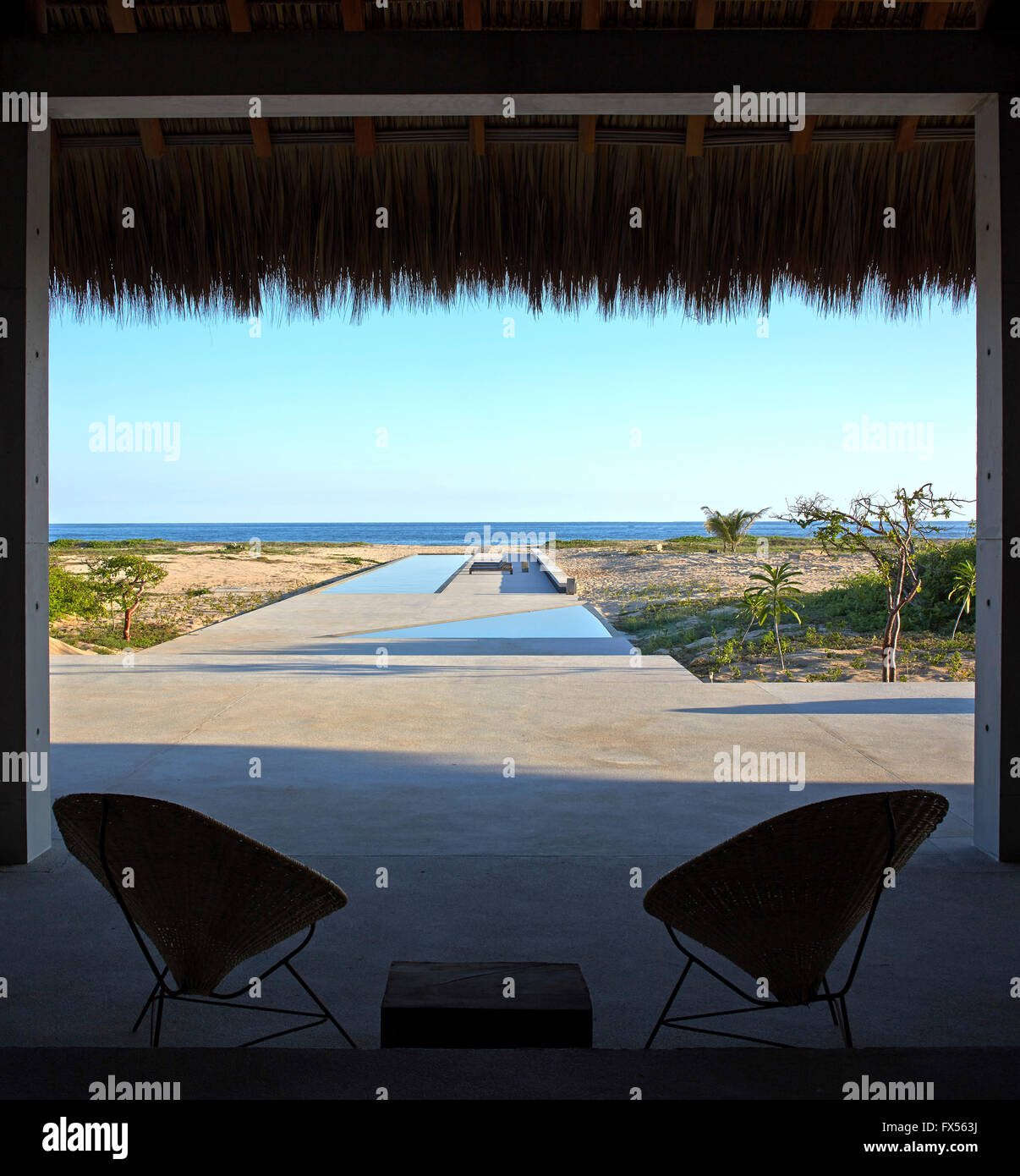 Vista dall'interno Palapa verso la piscina e il mare con stagliano sedie. Casa Wabi, Puerto Escondido, Messico. Architetto: Tadao Ando Foto Stock