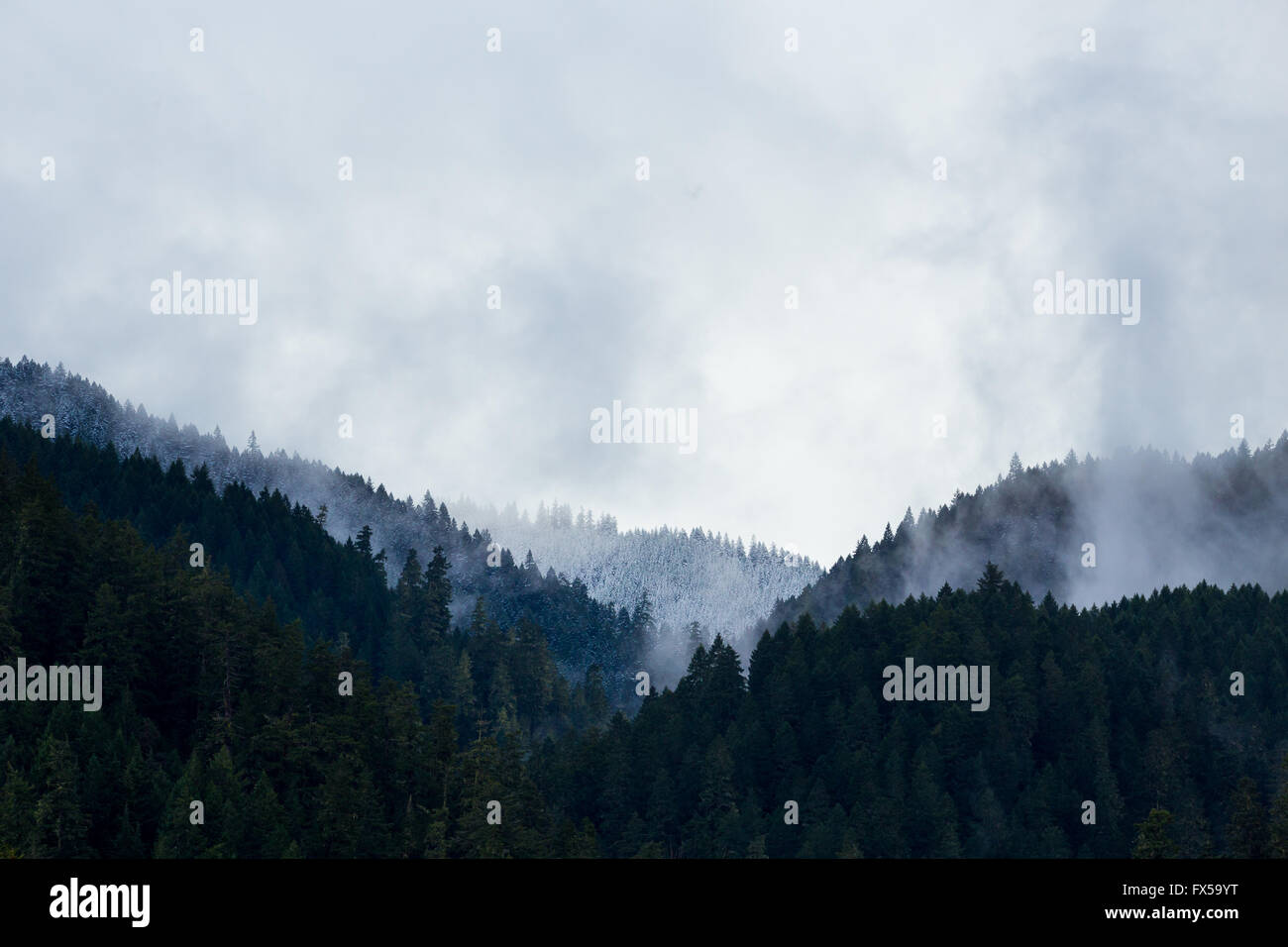 Colline e montagne con cime innevate e vapore in aumento. Foto Stock