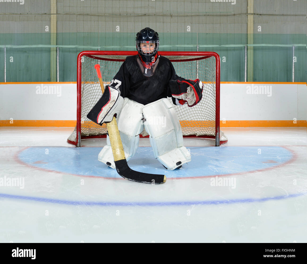 Un giovane Hockey Goalie Kid protegge il suo Net da un obiettivo. Fotografato nella piega di hockey di fresco con ghiaccio allagata. Foto Stock
