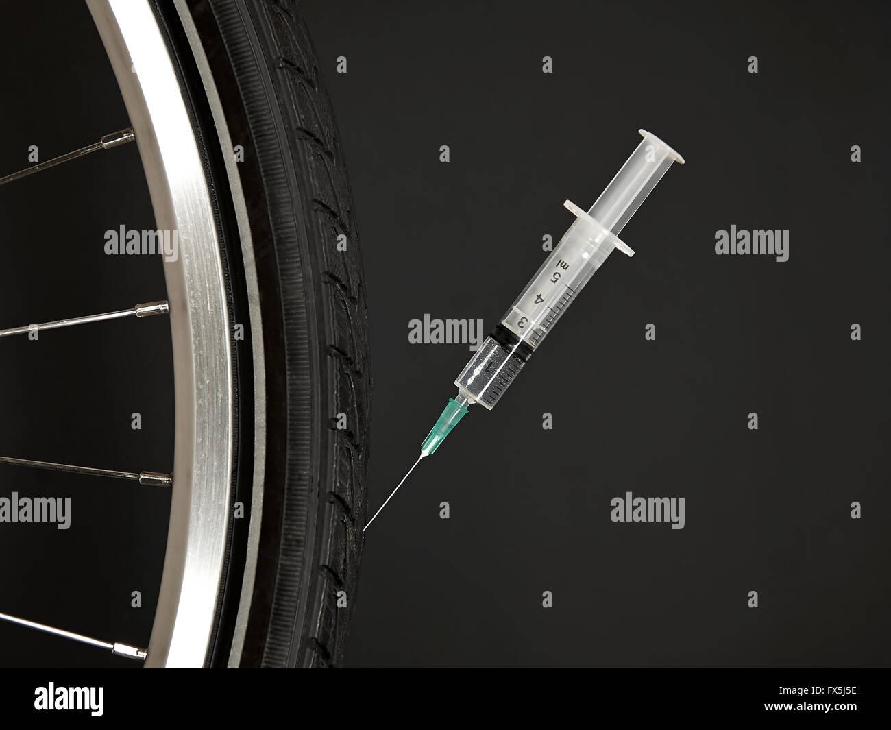 La ruota di bicicletta con una siringa in essa illustrante il doping Foto Stock