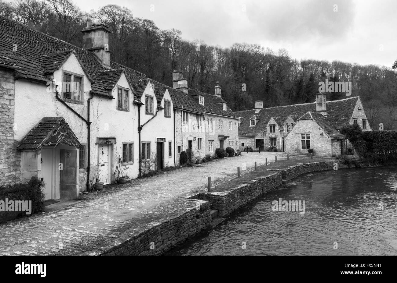 Immagine in bianco e nero dei pittoreschi cottage accanto al fiume Brook nel villaggio di Cotswold di Castle Combe, Wiltshire, Inghilterra, Regno Unito Foto Stock