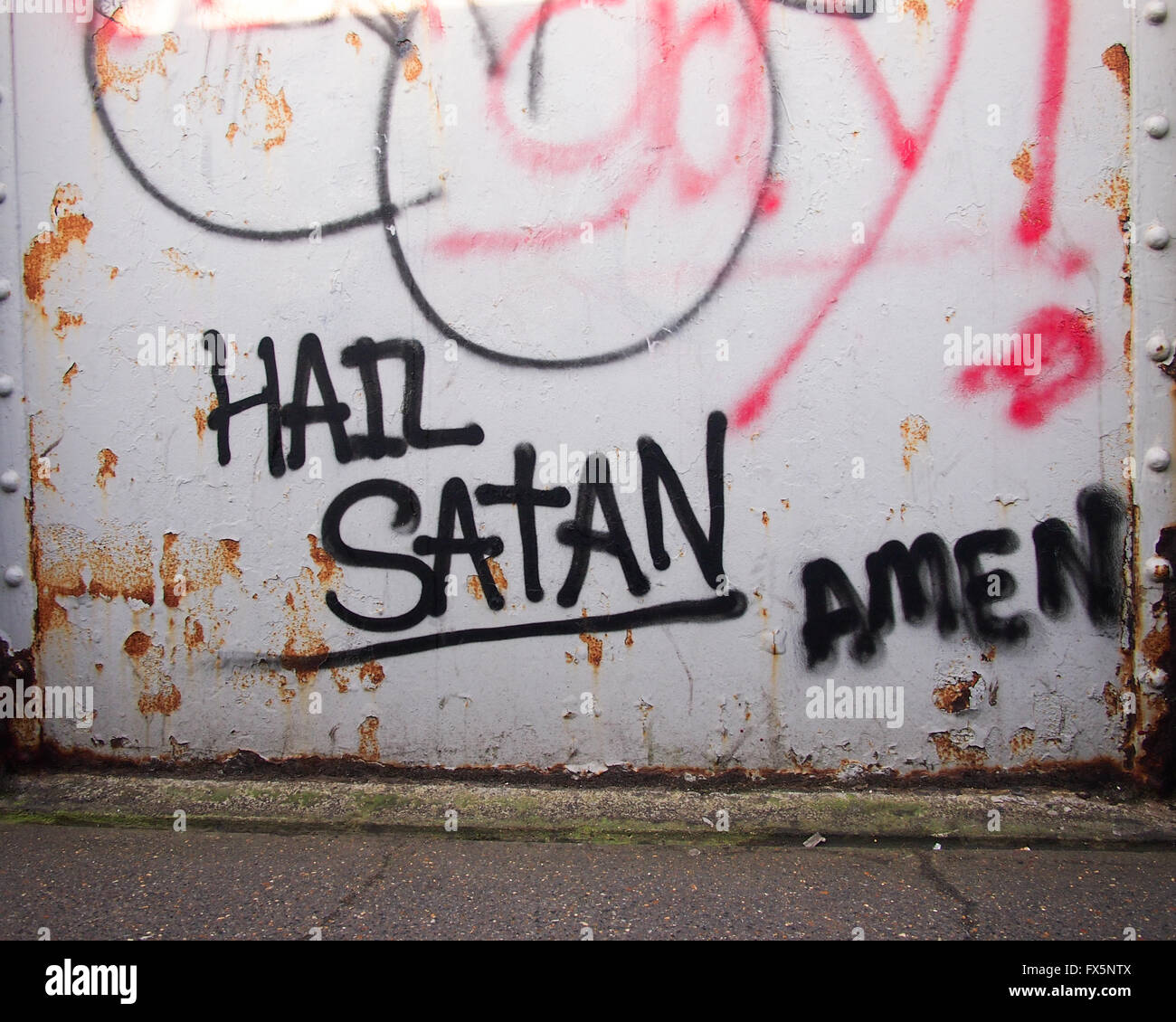 Graffiti su un acciaio ponte ferroviario proclamando 'hail satana" con la modifica "amen" accanto ad esso Foto Stock
