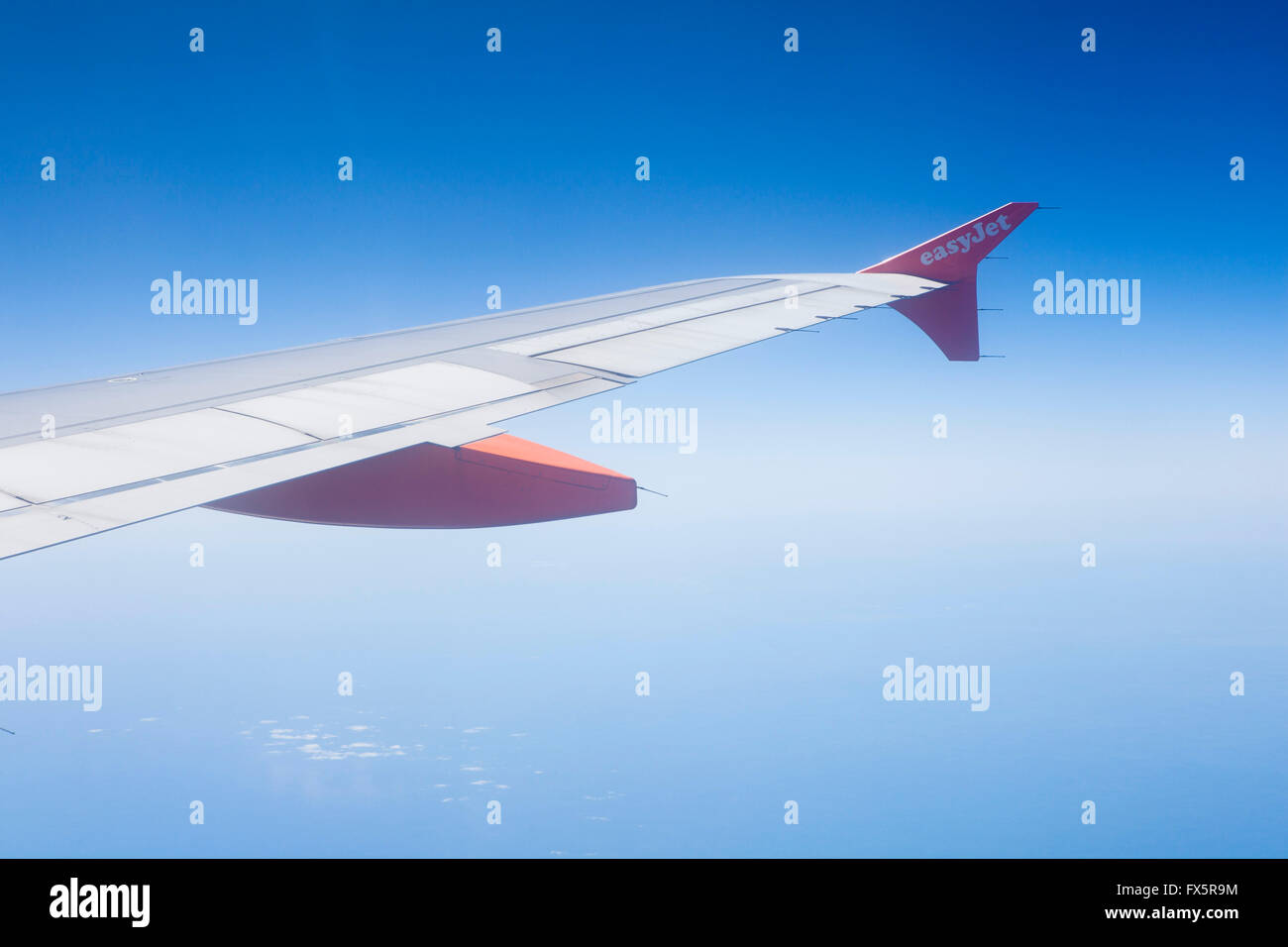 Vista dalla finestra di un aereo o di un aereo di linea che mostra l'ala del jet e un cielo blu profondo. Foto Stock