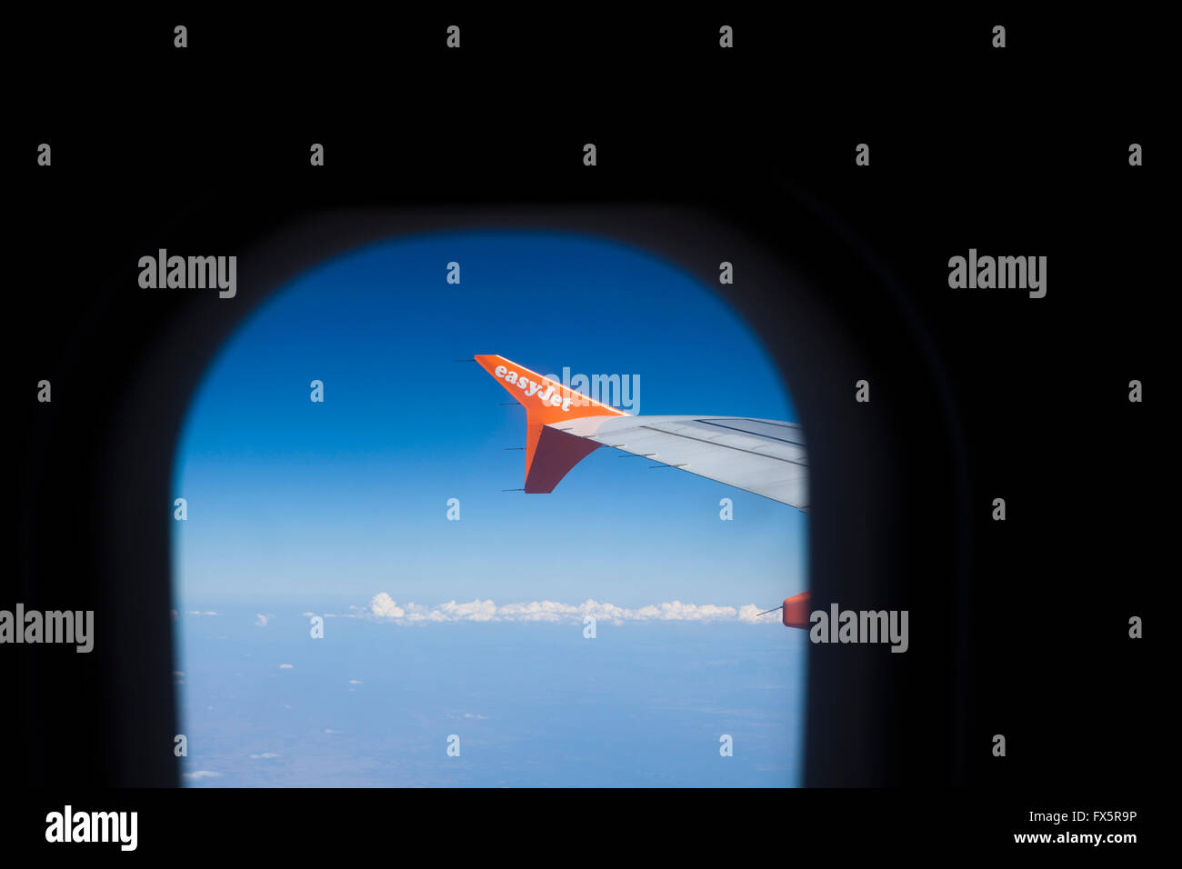 Vista dalla finestra di un aereo o di un aereo di linea che mostra l'ala del jet e un cielo blu profondo. Foto Stock