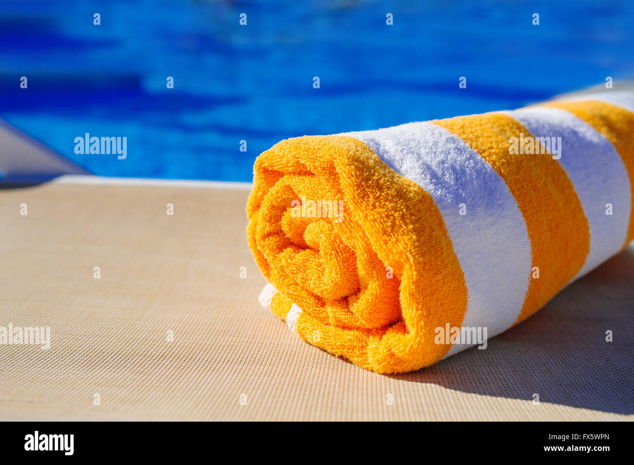 Arancione con asciugamano bianco su una sdraio sfondo della piscina Foto Stock