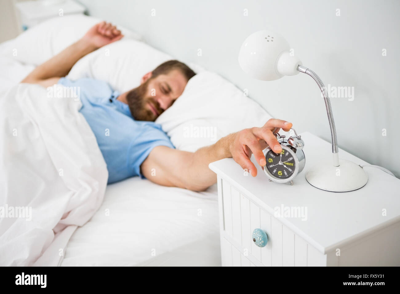 Sleeping uomo risvegliato da un allarme sul letto Foto Stock