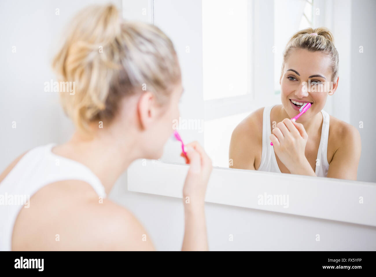 Giovane donna spazzolare i denti in bagno Foto Stock