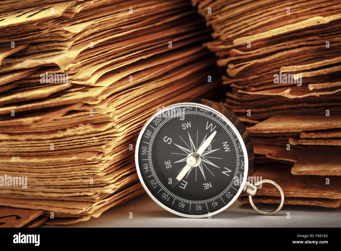 Pila di carte antiche con bussola in primo piano Foto Stock