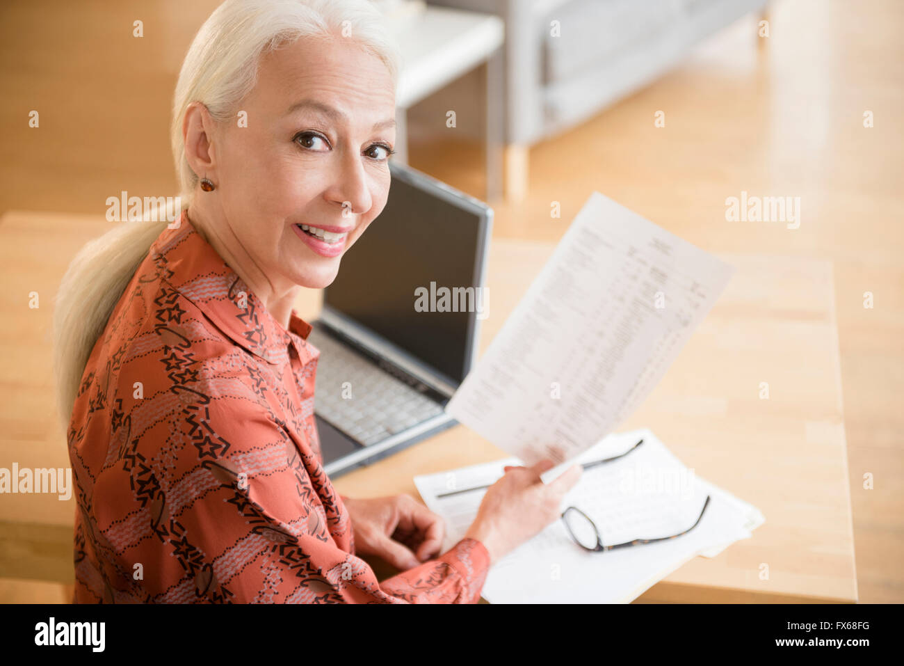 La donna caucasica il pagamento di fatture su laptop Foto Stock