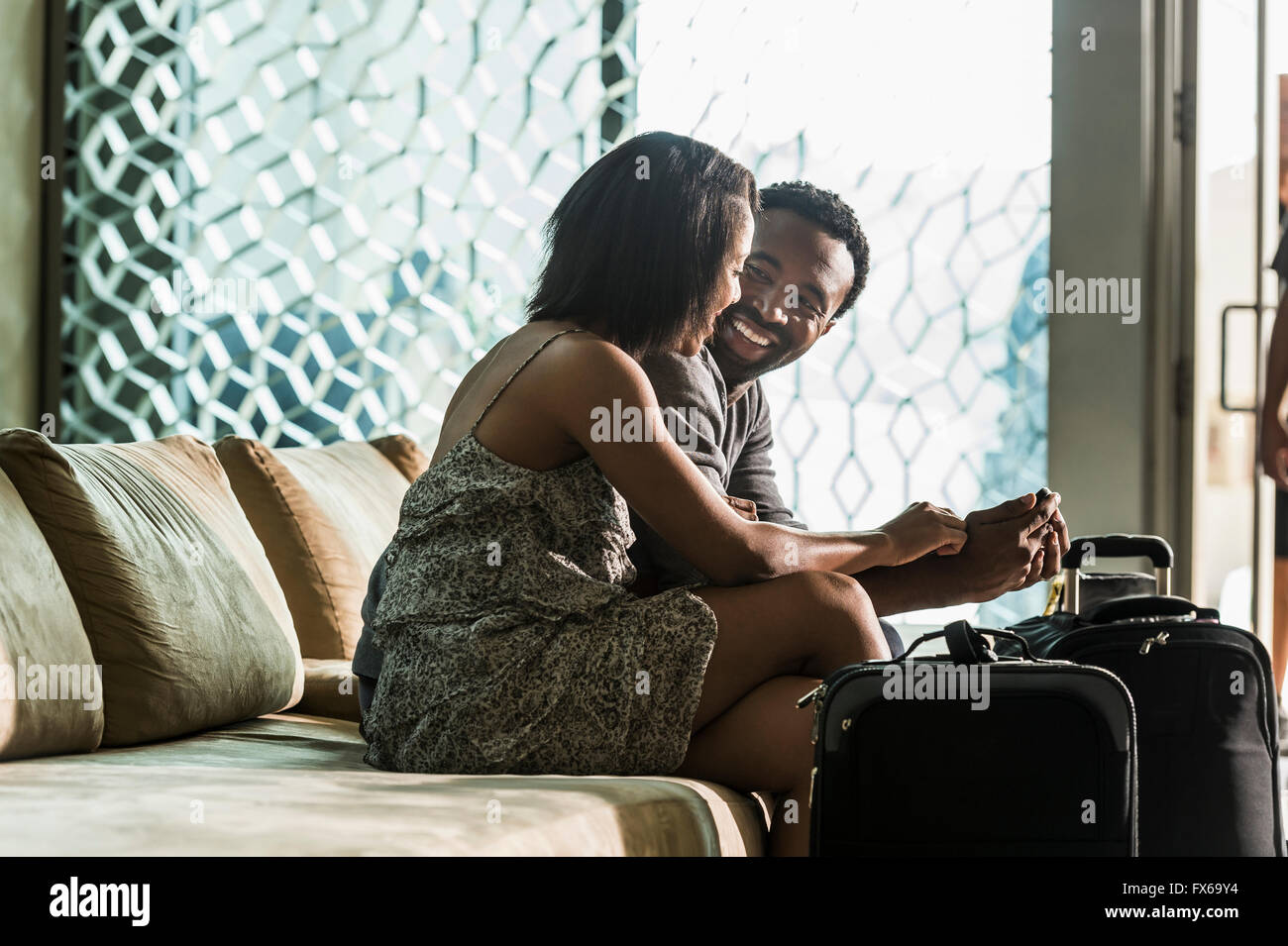 Giovane seduto su hotel lobby e divano Foto Stock