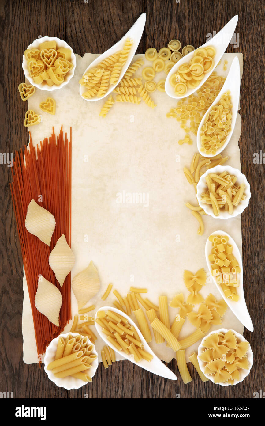 Selezione di pasta e pomodoro spaghetti cibo abstract formando un bordo sulla vecchia pergamena e oak sfondo. Foto Stock