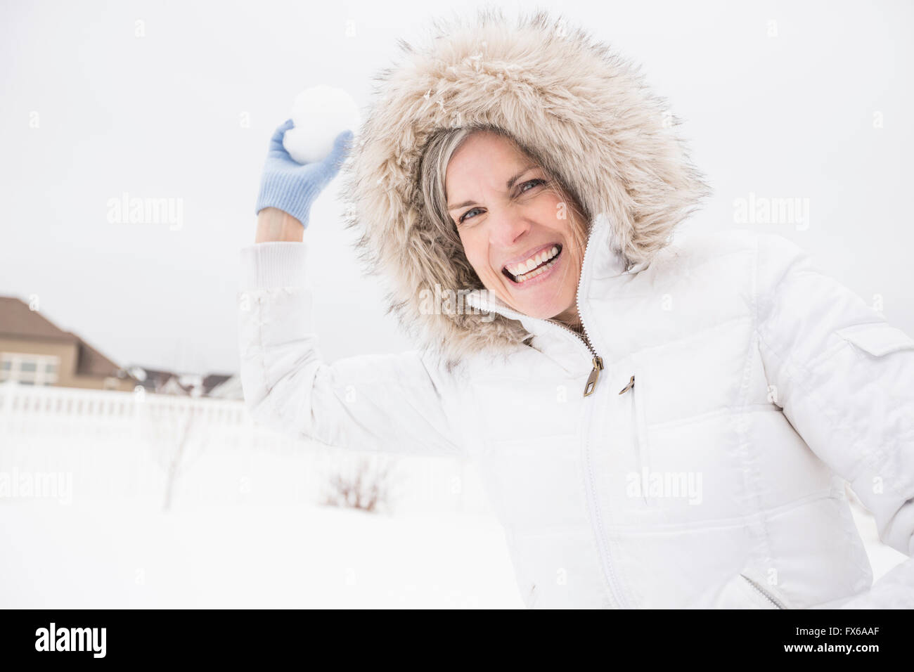 La donna caucasica lanciando palle di neve nella neve Foto Stock