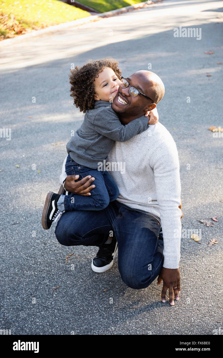 Ragazzo abbracciando padre all'aperto Foto Stock