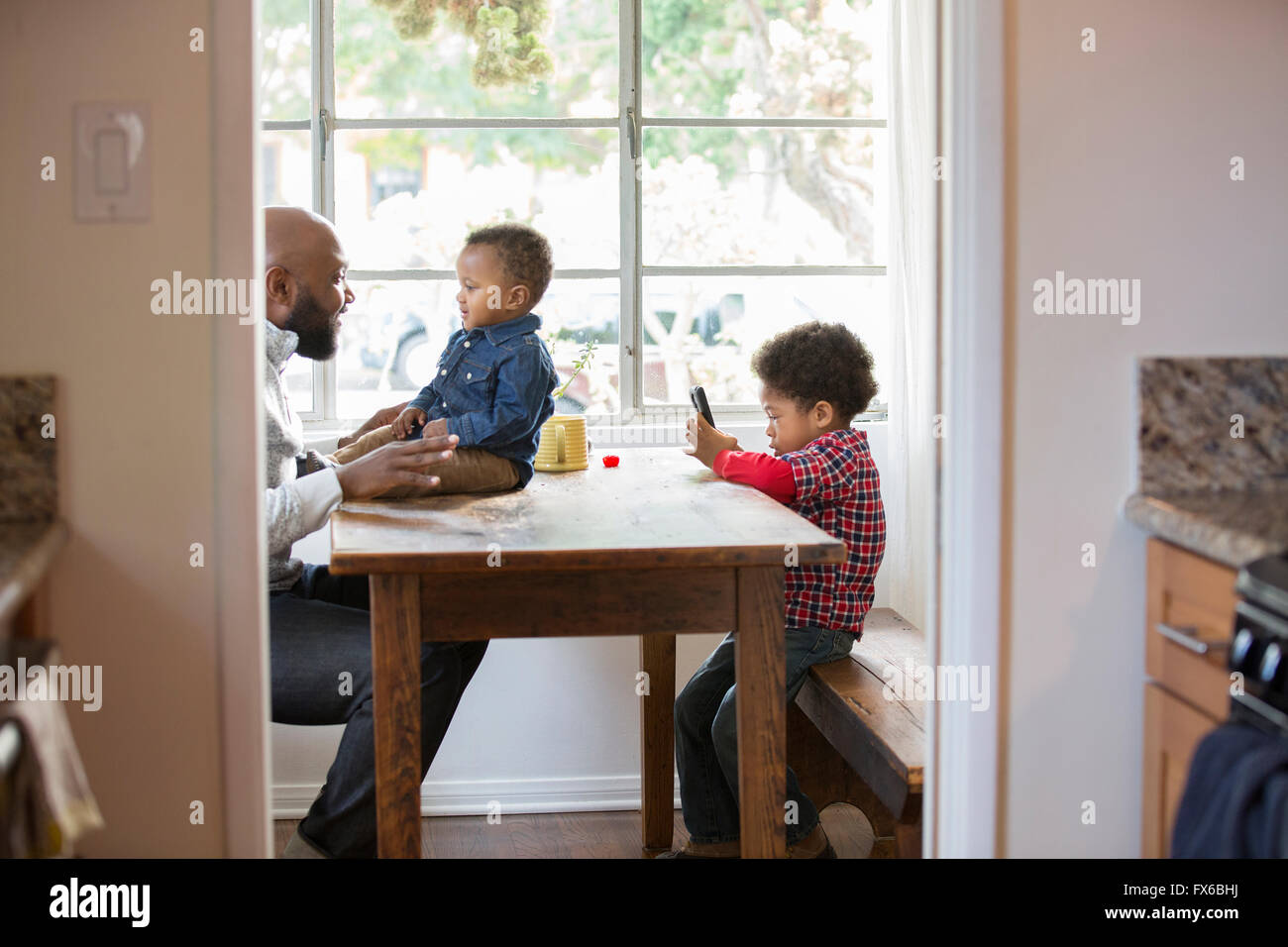 Padre e bambini seduti a tavola Foto Stock