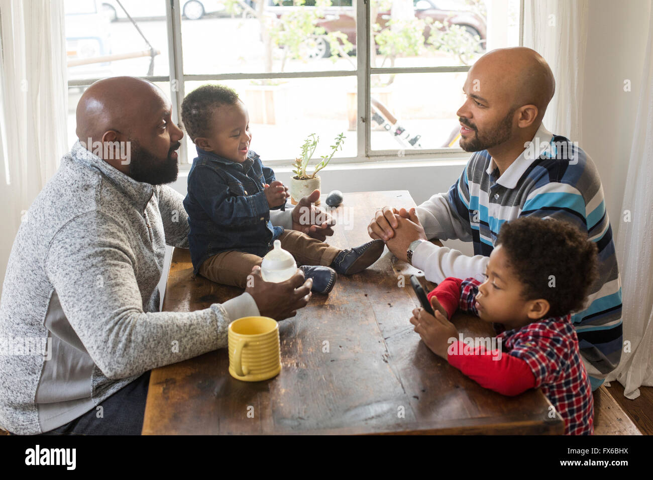 I padri e i bambini seduti a tavola Foto Stock