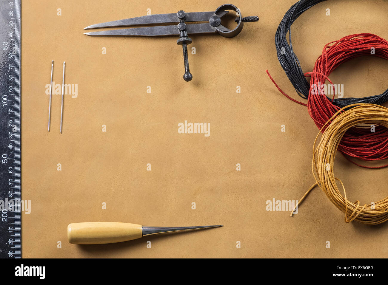 Ala divisore, cucitura awl con manico in legno e marrone, rosso e nero paraffinato filo di cotone sulla pelle Foto Stock