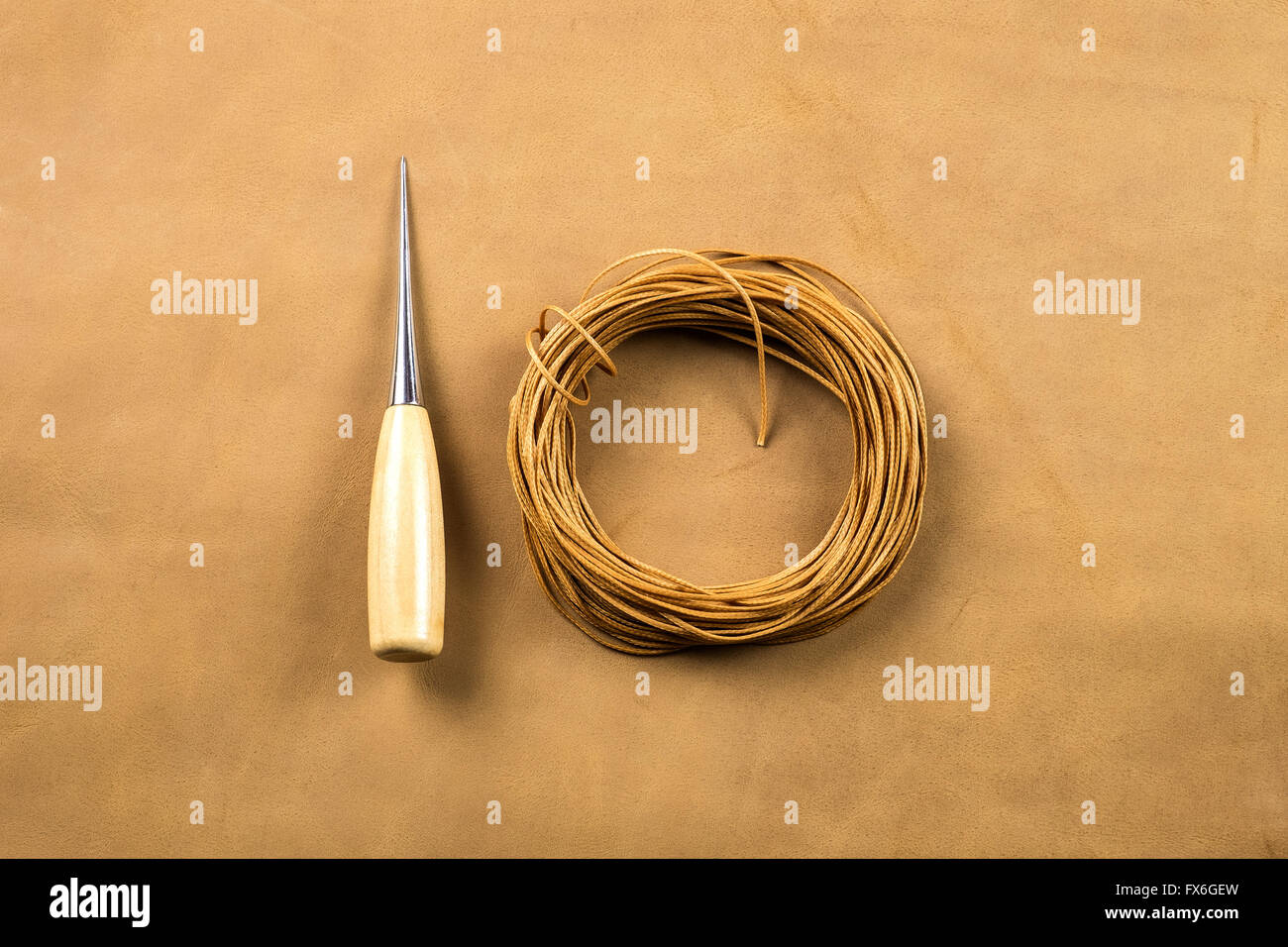 La cucitura awl con manico in legno e marrone cerato filo di cotone sulla pelle Foto Stock