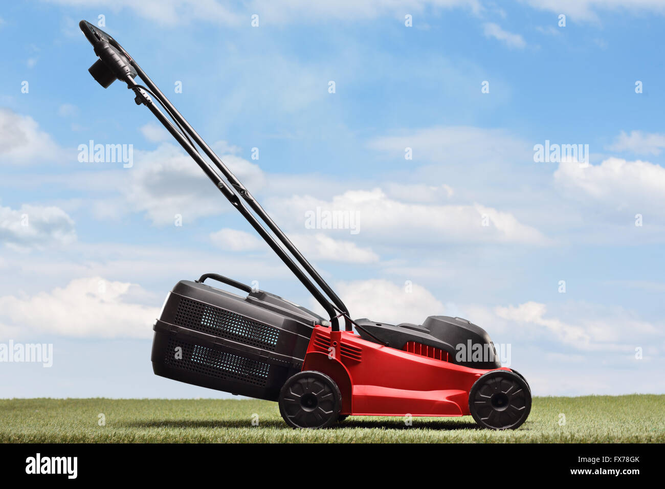 Tosaerba su un prato verde e blu sullo sfondo del cielo Foto Stock