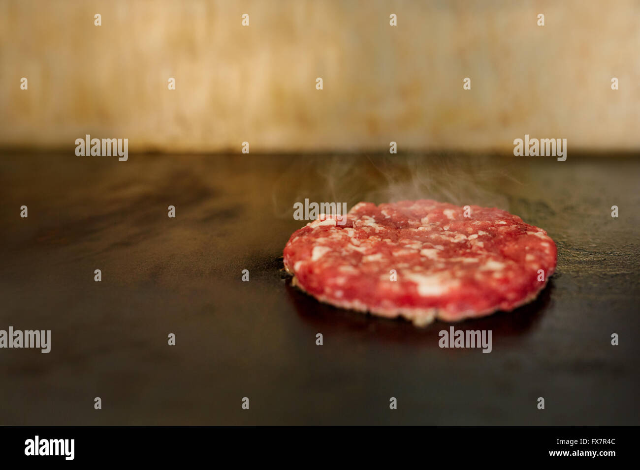 Hamburger patty con il condimento sfrigolante su un grill Foto Stock