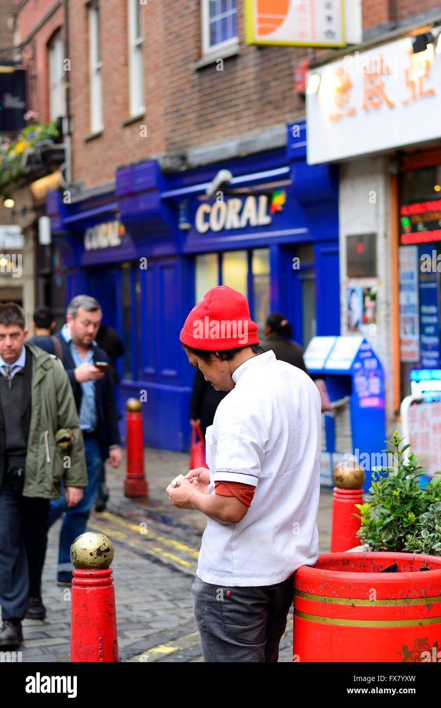 Giovane uomo cinese la laminazione di una sigaretta in China Town, Soho, Londra Foto Stock