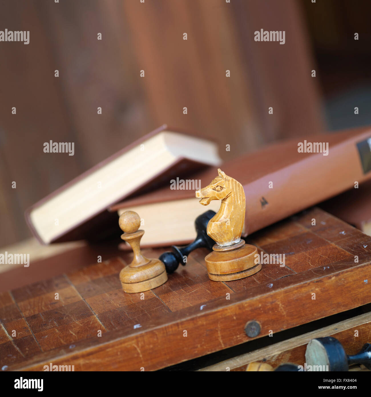 Alcuni pezzi di scacchi nel fuoco e libri di sfondo sfocato, il concetto di tempo libero giochi. Macro shot con il fuoco selettivo Foto Stock