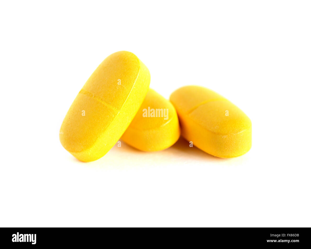 Extreme closeup di tre pillole di colore giallo su sfondo bianco Foto Stock