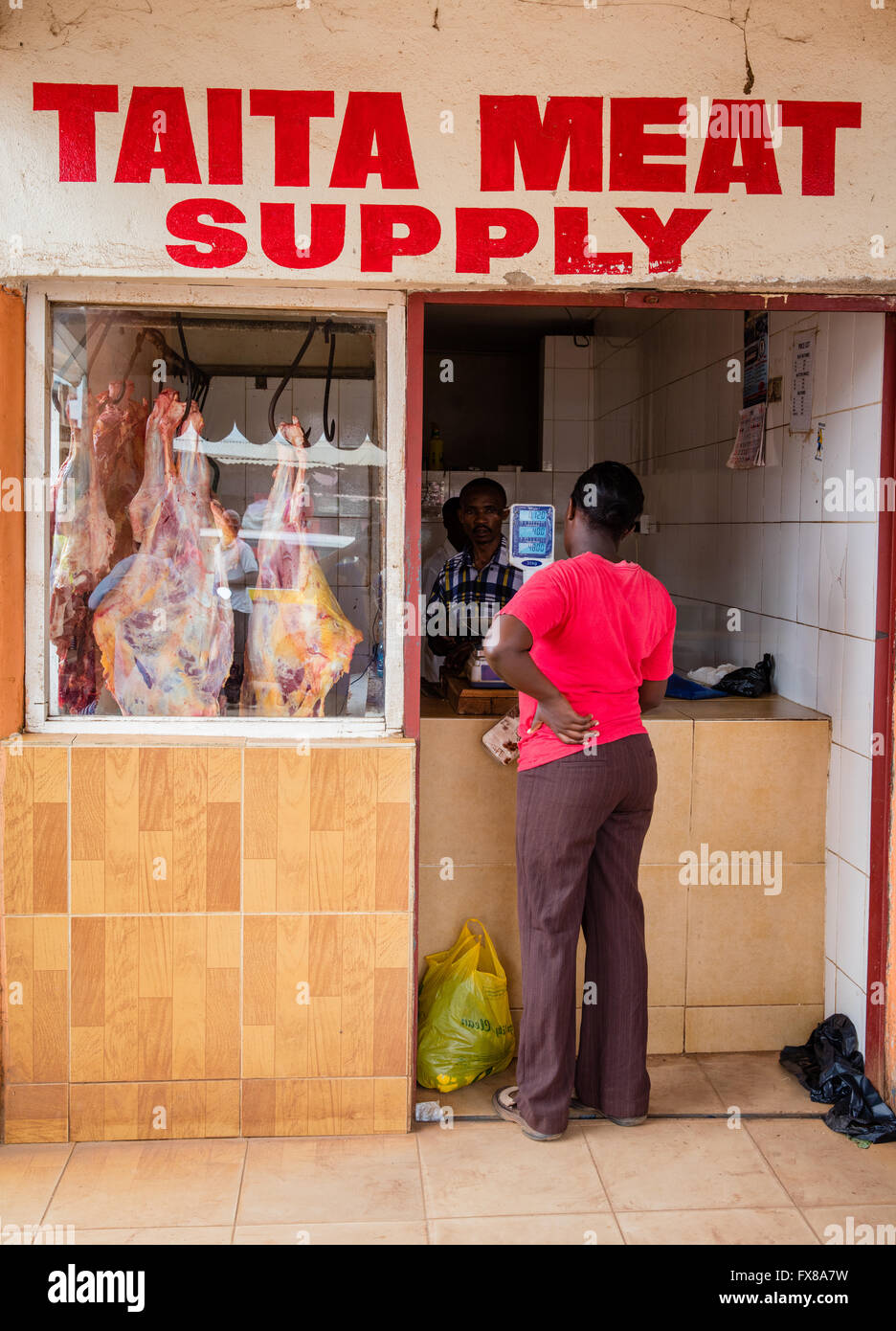 Configurazione tipica di una macelleria nella città di voi nella regione di Taita del sud del Kenya con carcasse appeso nella finestra Foto Stock