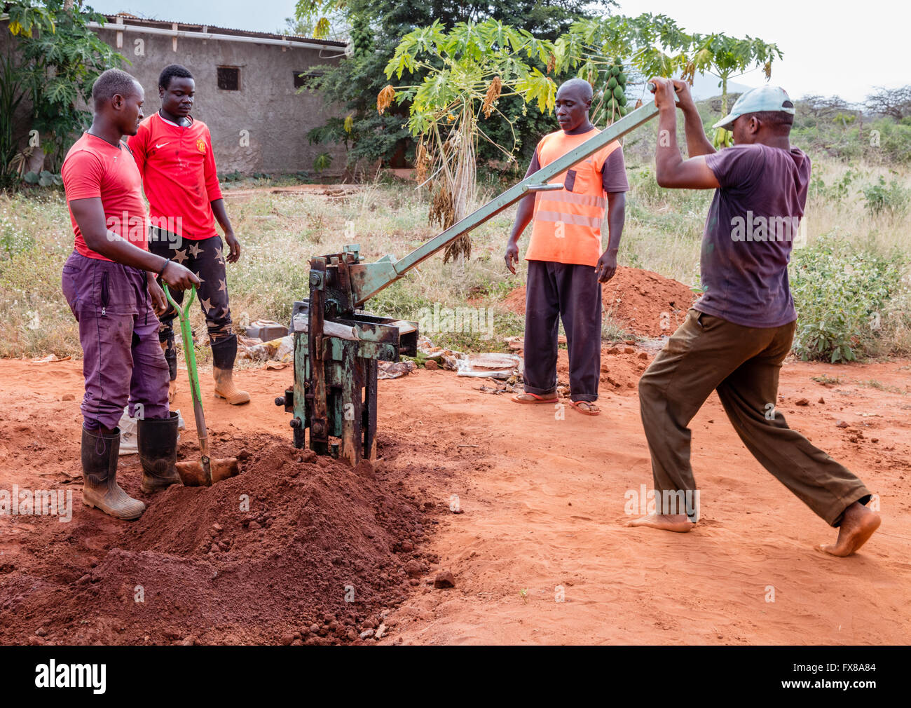 Fare mattoni ad incastro mediante stampaggio in pressa terra di sabbia e cemento su un edificio sito vicino a Voi Kenya Africa Foto Stock